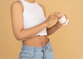 Close-up of a woman applying moisturizing cream in a studio setting with warm tones.